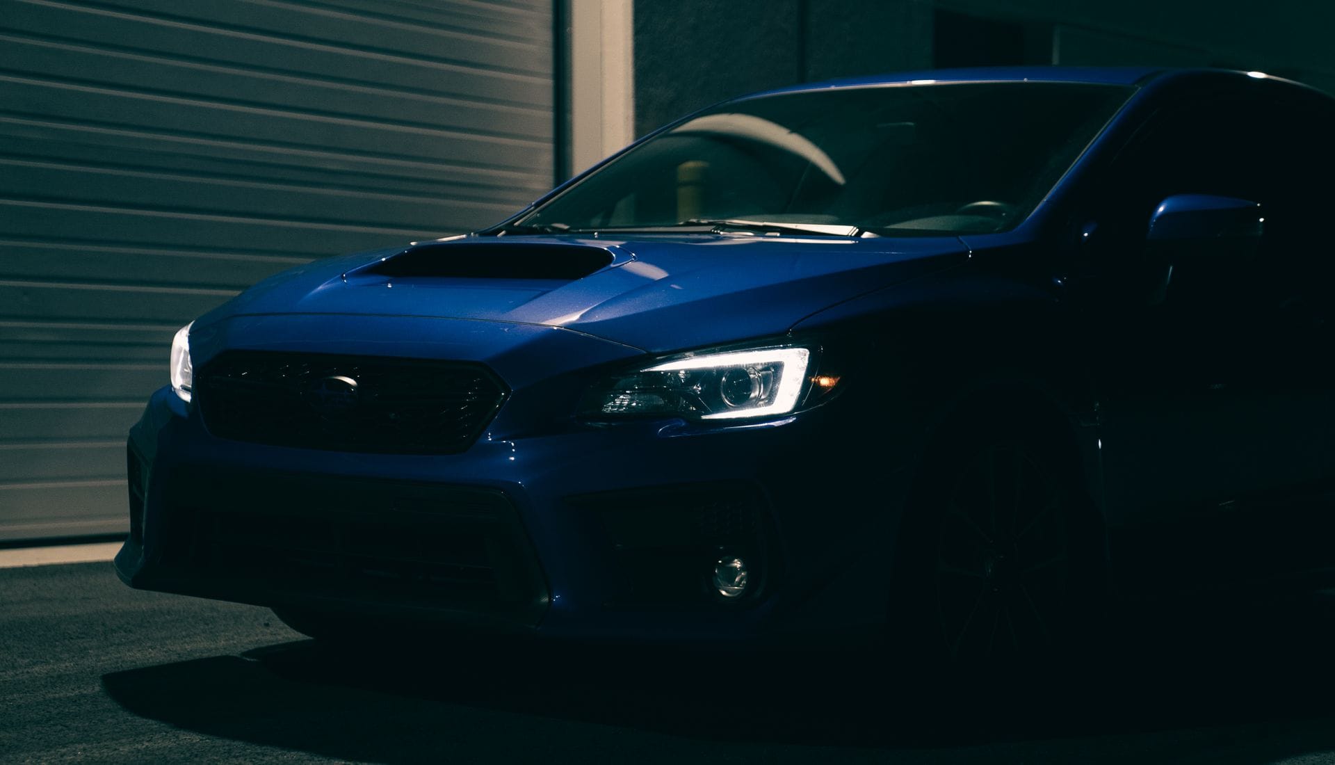 Carro esportivo azul com acabamento brilhante numa garagem escura